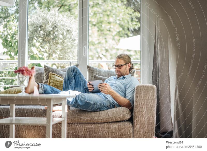 Mann entspannt sich auf der Couch mit Tablette Sofa Couches Liege Sofas entspanntheit relaxt Männer männlich Tablet Computer Tablet-PC Tablet PC iPad