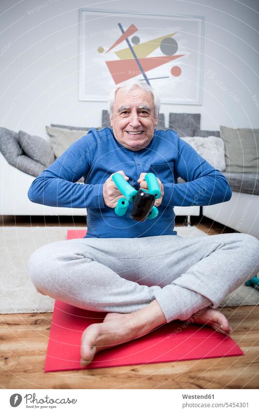 Älterer Mann macht zu Hause Muskeltraining Trainieren Übung Üben Übungen Hantel Hanteln sitzen sitzend sitzt üben ausüben trainieren aktiv Fitness Gesundheit