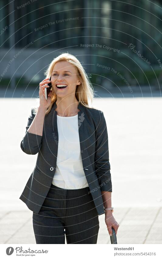Porträt einer lachenden blonden Geschäftsfrau am Telefon Geschäftsfrauen Businesswomen Businessfrauen Businesswoman Portrait Porträts Portraits telefonieren