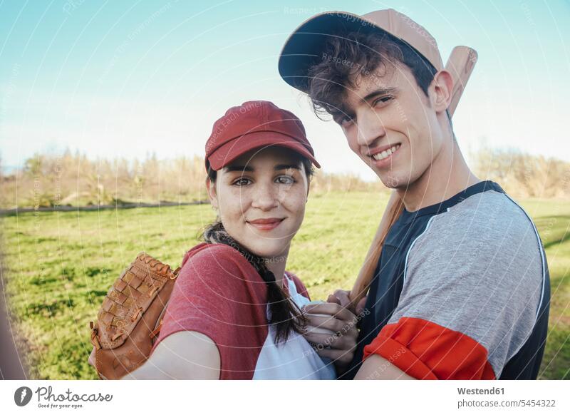 Porträt eines lächelnden jungen Paares mit Baseballausrüstung im Park Selfie Selfies Pärchen Partnerschaft Baseballspiel Baseballspieler Baseballer Mensch