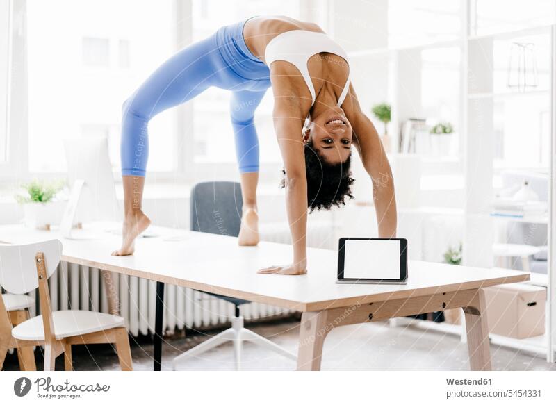 Junge Frau praktiziert Yoga mit Laptop an ihrer Seite fit Notebook Laptops Notebooks Training trainieren lernen üben ausüben Übung weiblich Frauen Online
