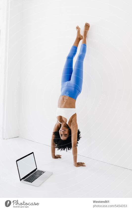 Junge Frau praktiziert Yoga mit Laptop an ihrer Seite üben ausüben Übung trainieren Training Online fit weiblich Frauen Notebook Laptops Notebooks lernen
