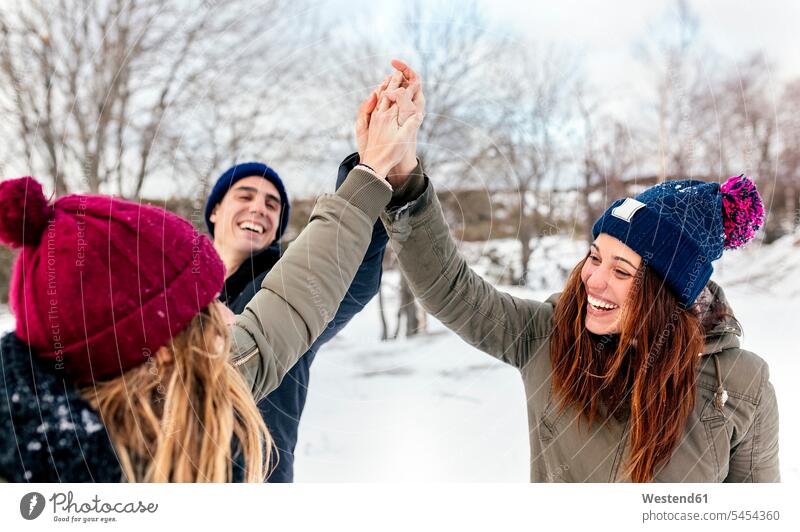 Drei Freunde reichen sich die Hände im Schnee Winter winterlich Winterzeit Spaß Spass Späße spassig Spässe spaßig Freundschaft Kameradschaft Wetter Hand in Hand
