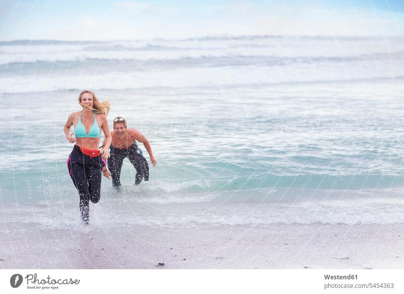 Ein Paar, das Spaß am Meer hat Pärchen Paare Partnerschaft lachen Spass Späße spassig Spässe spaßig Strand Beach Straende Strände Beaches Mensch Menschen Leute