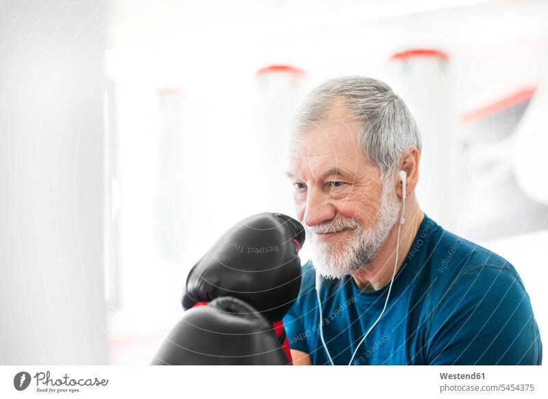 Senioren im Fitnessstudio mit Kopfhörern und Boxhandschuhen ausstatten lächeln Fitnessclubs Fitnessstudios Turnhalle Boxer boxen trainieren ältere Männer