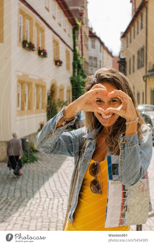 Deutschland, Rothenburg ob der Tauber, Porträt einer glücklichen Frau, die mit ihren Fingern das Herz formt weiblich Frauen Erwachsener erwachsen Mensch