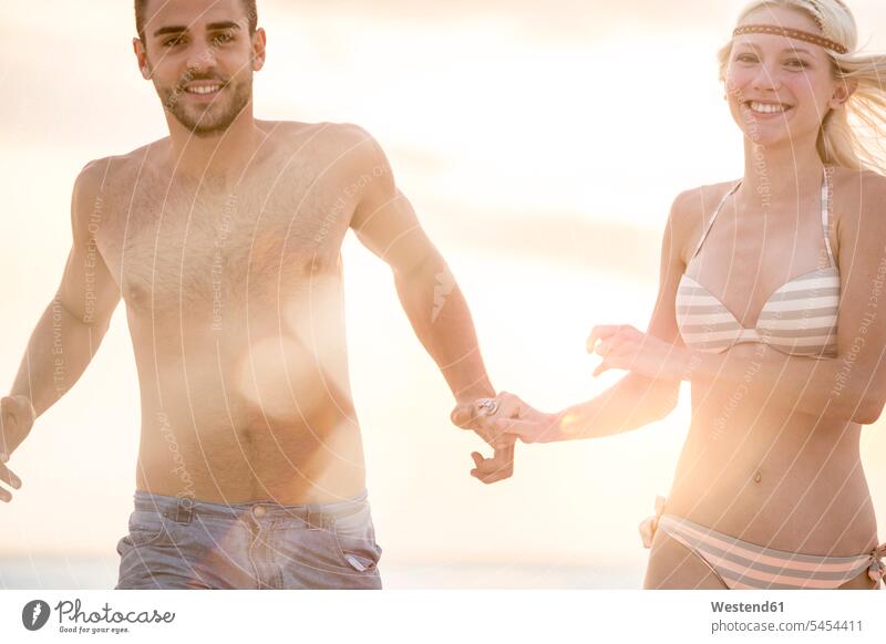 Junges Paar rennt am Strand und hält sich an den Händen Urlaub Ferien Beach Straende Strände Beaches Meer Meere glücklich Glück glücklich sein glücklichsein
