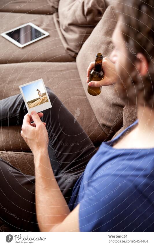 Mann sitzt auf Couch mit Bierflasche und schaut auf Sofortbild Foto Fotos Männer männlich Bild Bildnis Bilder Erwachsener erwachsen Mensch Menschen Leute People