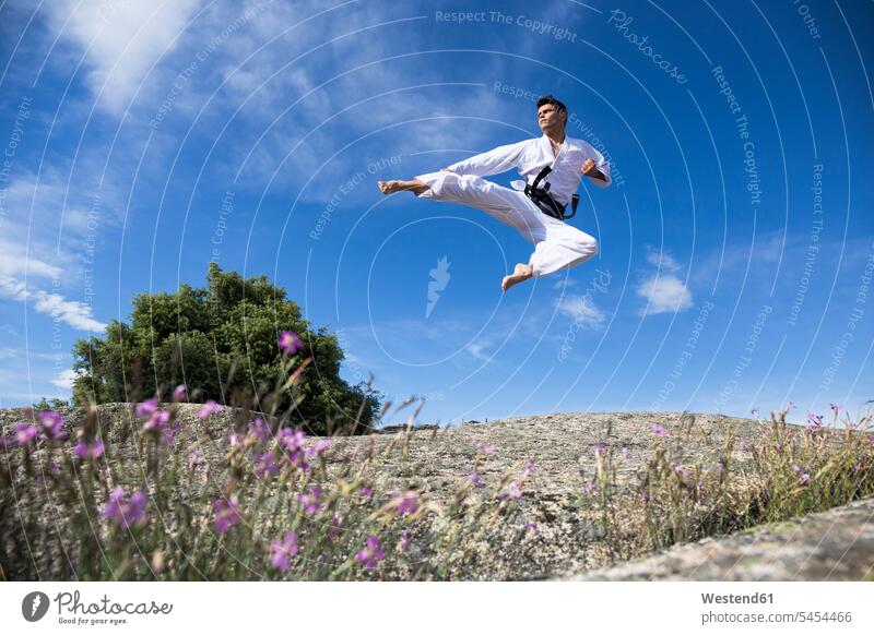 Mann macht einen Sprungtritt während eines Kampfsporttrainings trainieren springen hüpfen treten kicken tretend stoßen Kampfsportart Kampfsportarten Kampfkunst