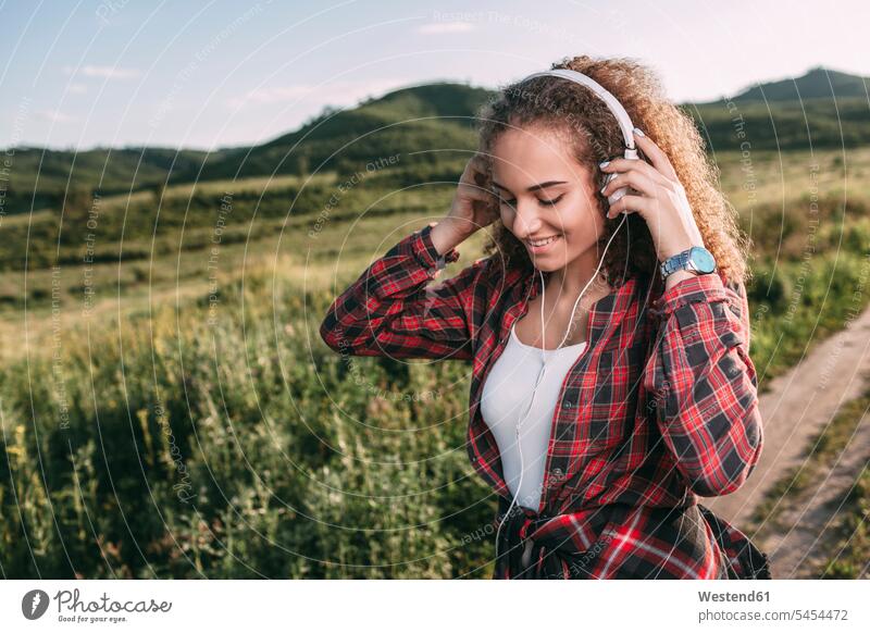 Teenager-Mädchen beim Musikhören mit Kopfhörern in der Natur Teenagerin junges Mädchen Teenagerinnen weiblich junge Frau Kopfhoerer Jugendliche Heranwachsende