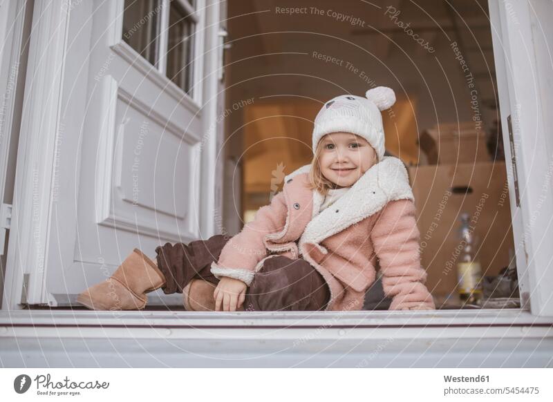 Junges Mädchen sitzt im Eingang, Pappkarton Umzug umziehen weiblich Mantel Mäntel Jacke Umzugskarton Umzugskiste Umzugskisten Umzugskartons sitzen sitzend
