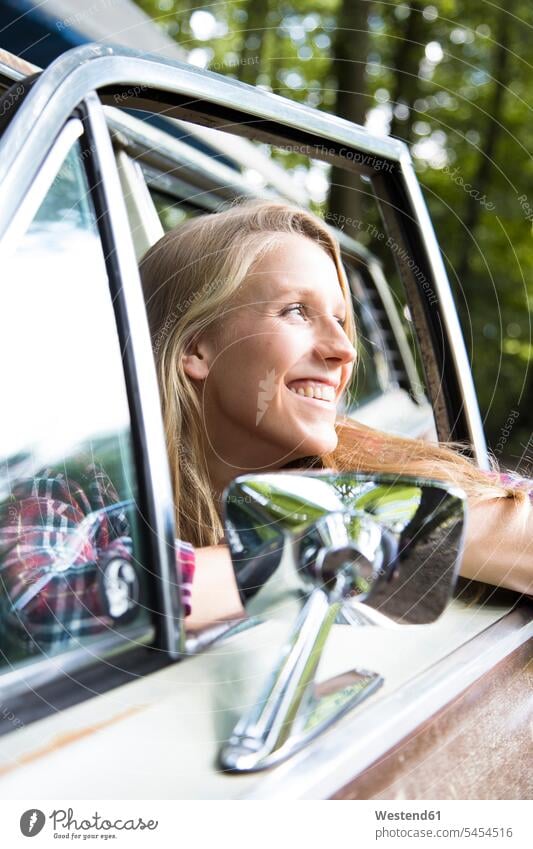 Glückliche junge Frau im Auto im Wald Forst Wälder glücklich glücklich sein glücklichsein weiblich Frauen Wagen PKWs Automobil Autos Erwachsener erwachsen