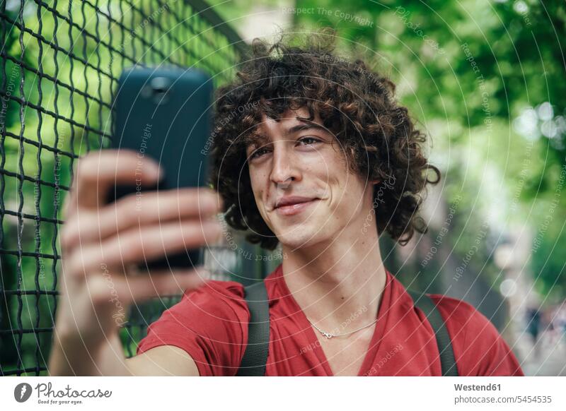 Junger Mann macht ein Selfie mit Smartphone Selfies Handy Mobiltelefon Handies Handys Mobiltelefone Männer männlich Telefon telefonieren Kommunikation
