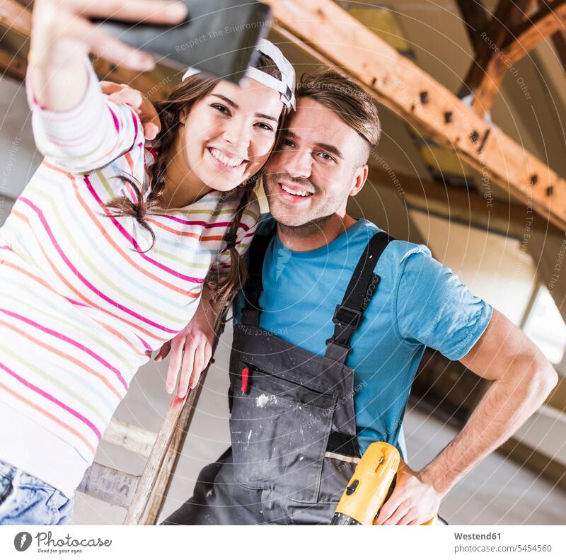 Junges Paar renoviert sein neues Haus und macht dabei Selfies mit dem Smartphone Heimwerken Do-it-Yourself DIY Pärchen Paare Partnerschaft fröhlich Fröhlichkeit