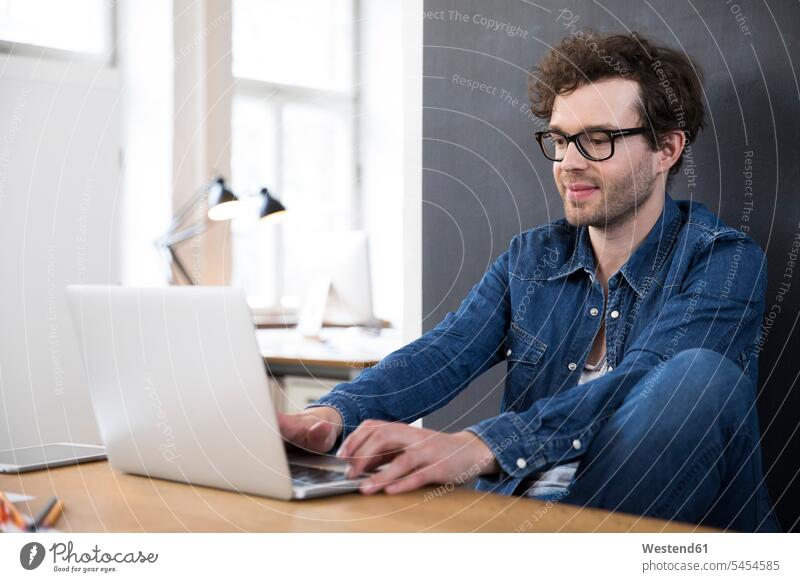 Lächelnder Mann mit Laptop im Büro Office Büros Arbeitsplatz Arbeitsstätte Arbeitstelle Notebook Laptops Notebooks Männer männlich lächeln arbeiten Computer
