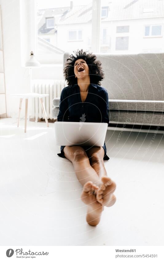 Junge Frau sitzt auf dem Boden und benutzt einen Laptop Zuhause zu Hause daheim barfuß nackte Füße nackter Fuss barfuessig barfüssig nackter Fuß barfuss