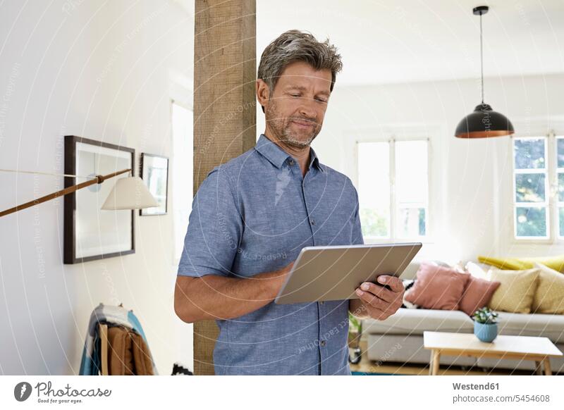 Reifer Mann zu Hause mit digitalem Tablett Internet Tablet Computer Tablet-PC Tablet PC iPad Tablet-Computer Kontrolle kontrollieren Smart Home smarthome
