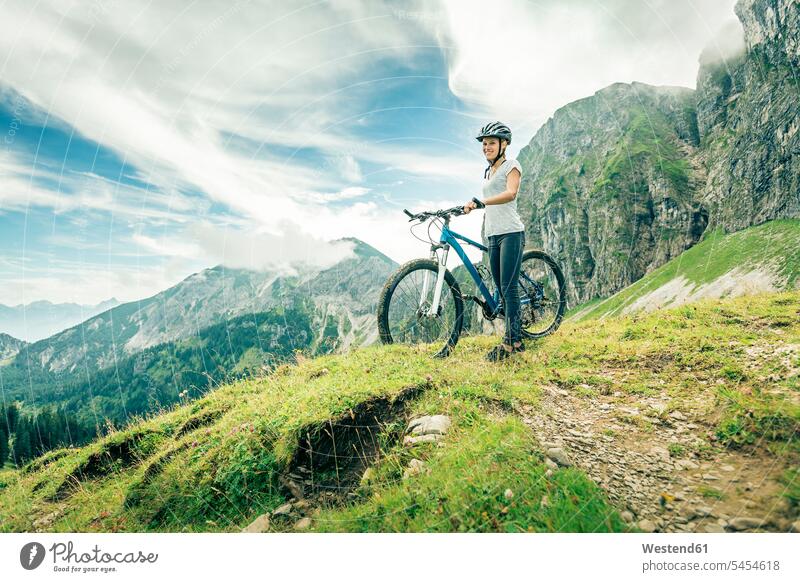 Deutschland, Bayern, Pfronten, lächelndes Teenagermädchen mit Mountainbike auf Almwiese bei Aggenstein Aussicht Ausblick Ansicht Überblick stehen stehend steht