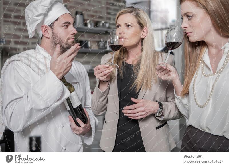Koch mit zwei Frauen in der Küche bei einer Weinprobe Küchenchefs Köche Koeche Kuechenchef Kuechenchefs Rotwein Rotweine Kochkurs Gastronomie Weine Alkohol