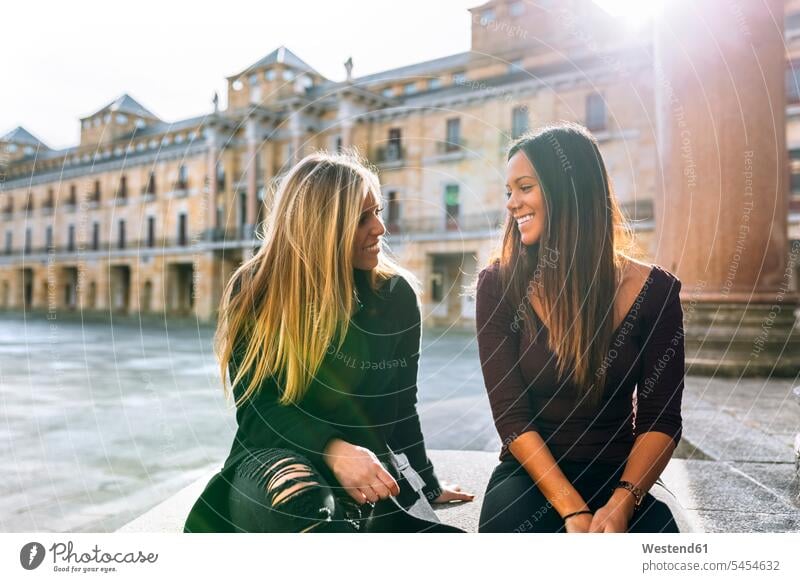 Zwei lächelnde junge Frauen unterhalten sich auf dem Stadtplatz Freundinnen weiblich Freunde Freundschaft Kameradschaft Erwachsener erwachsen Mensch Menschen