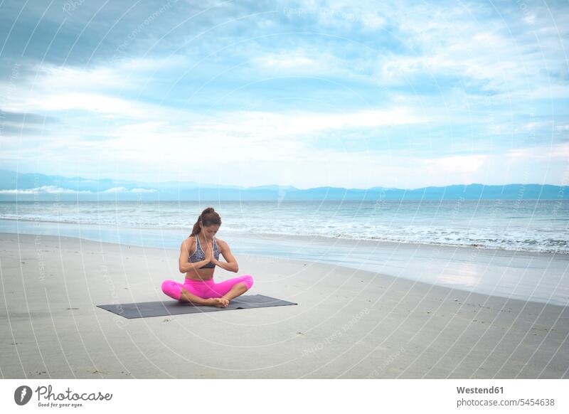 Frau praktiziert Yoga am Strand Beach Straende Strände Beaches fit Yoga-Übungen Yogauebungen Yogaübungen Jogauebung Jogauebungen üben ausüben trainieren
