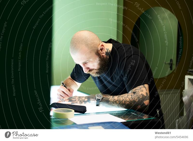 Tätowierer entwirft Motiv auf Leuchttisch im Studio zeichnen Zeichnung Tattoo Tätowierungen Tatoos Taetowierung Tattoos Taetowierungen entwerfen Entwurf Mann