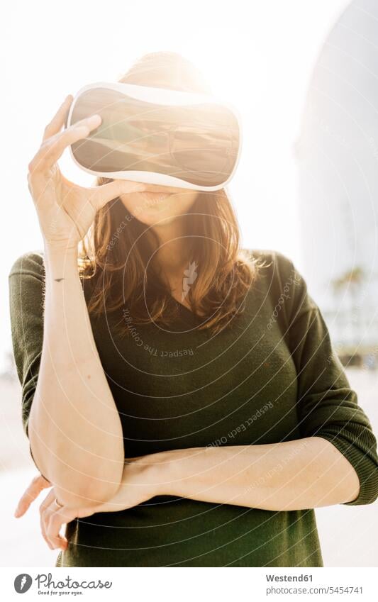 Junge Frau mit VR-Brille im Freien Virtuelle Realität Virtuelle Realitaet weiblich Frauen Erwachsener erwachsen Mensch Menschen Leute People Personen Spanien 3D