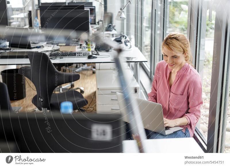 Lächelnde Frau mit Laptop im Büro Notebook Laptops Notebooks lächeln Office Büros weiblich Frauen Computer Rechner Arbeitsplatz Arbeitsstätte Arbeitstelle