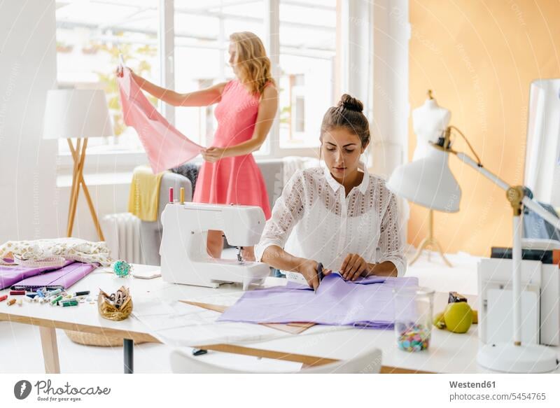 Zwei junge Frauen im Modeatelier nähen naehen Studio Atelier Studios Ateliers modisch Fashion weiblich Erwachsener erwachsen Mensch Menschen Leute People