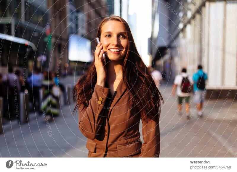 USA, New York, Manhattan, lächelnde junge Geschäftsfrau am Telefon telefonieren anrufen Anruf telephonieren Portrait Porträts Portraits Geschäftsfrauen
