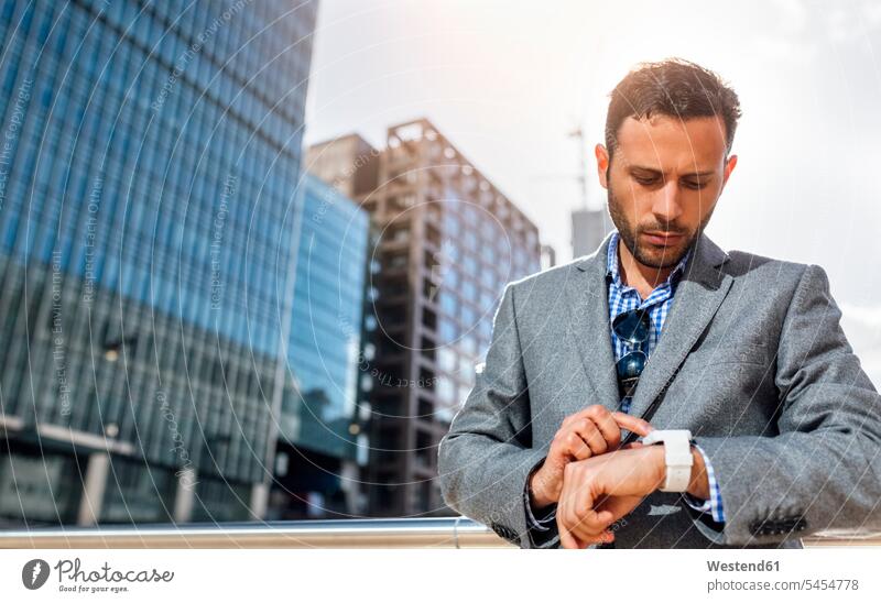 Geschäftsmann, der die Uhrzeit in der Stadt überprüft Businessmann Businessmänner Geschäftsmänner Armbanduhr Armbanduhren Geschäftsleute Geschäftspersonen