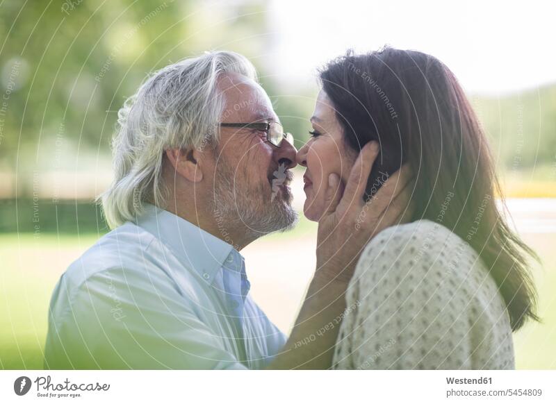 Älteres Paar küsst sich im Freien lächeln Pärchen Paare Partnerschaft küssen Küsse Kuss Mensch Menschen Leute People Personen Seniorenpaar älteres Paar