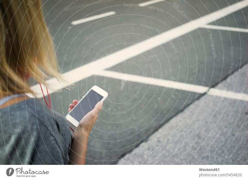 Junge Frau mit Handy am Straßenrand, Teilansicht Straßenränder Strassenrand Strassenraender Smartphone iPhone Smartphones weiblich Frauen Mobiltelefon Handies