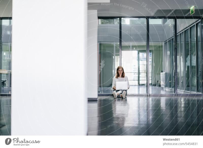 Geschäftsfrau sitzt am Boden in einem leeren Büro und benutzt einen Laptop Office Büros auf dem Boden sitzen auf dem Boden sitzend arbeiten Arbeit Notebook