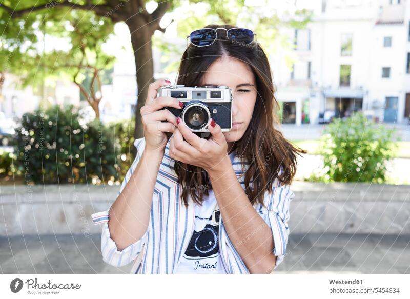 Junge Frau, die mit einer Oldtimer-Kamera fotografiert Vintage altmodisch Fotoapparat Fotokamera Kameras fotografieren weiblich Frauen Erwachsener erwachsen