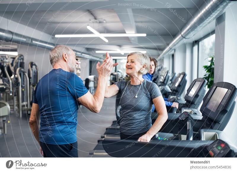 Glückliche ältere Männer und Frauen nach dem Training im Fitnessstudio Senioren alte trainieren abklatschen High Five Fitnessclubs Fitnessstudios Turnhalle