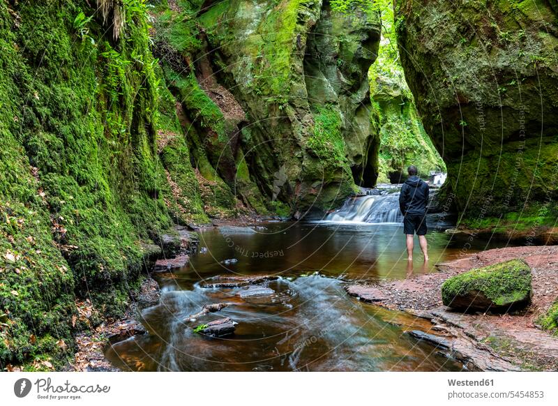 Großbritannien, Schottland, Trossachs-Nationalpark, Finnich-Glen-Canyon, The Devil's Pulpit, River Carnock Burn, männlicher Tourist im Wasser stehend Felswand