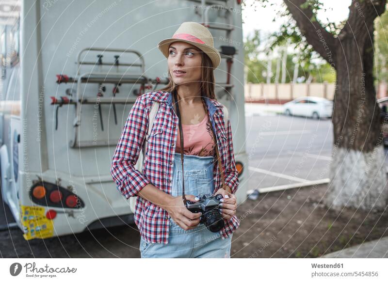 Junge Frau mit einer Kamera auf einem Parkplatz, die sich umsieht Fotoapparat Fotokamera weiblich Frauen Erwachsener erwachsen Mensch Menschen Leute People