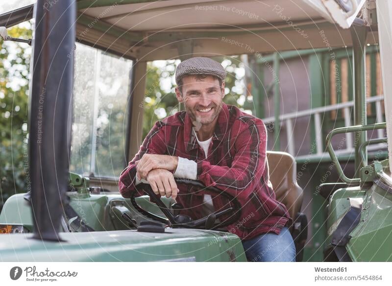 Porträt eines selbstbewussten Landwirts auf einem Traktor lächeln Portrait Porträts Portraits Mann Männer männlich Bauer Landwirte Bauern Schlepper Traktoren
