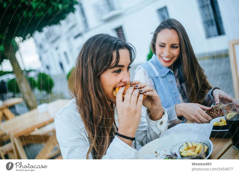 Zwei Frauen essen Hamburger in einem Straßenrestaurant weiblich Burger essend Erwachsener erwachsen Mensch Menschen Leute People Personen Fleisch Fastfood
