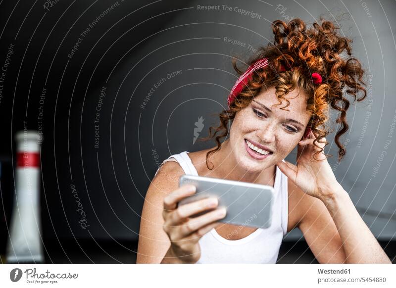 Lächelnde rothaarige Frau mit Handy in der Hand lächeln Mobiltelefon Handies Handys Mobiltelefone weiblich Frauen Telefon telefonieren Kommunikation