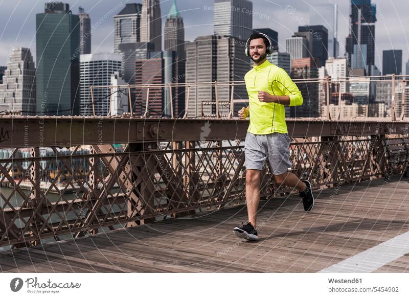 USA, New York City, Mann läuft auf der Brooklyn Brige Joggen Jogging Kopfhörer Kopfhoerer Männer männlich Brücke Bruecken Brücken laufen rennen Fitness fit
