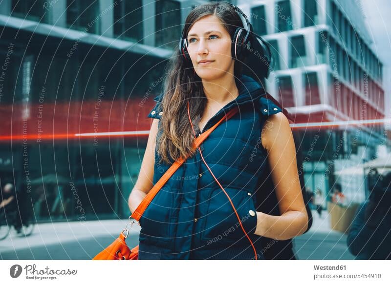 Junge Frau mit Kopfhörern in der Stadt Musik Kopfhoerer weiblich Frauen Erwachsener erwachsen Mensch Menschen Leute People Personen staedtisch städtisch