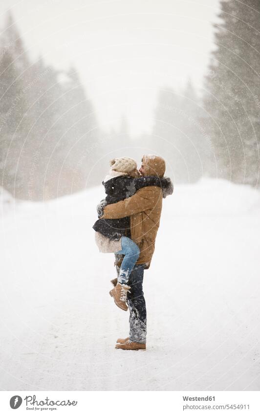 Glückliches junges Paar von Angesicht zu Angesicht in schneebedeckter Winterlandschaft Winterlandschaften Pärchen Paare Partnerschaft Landschaft Landschaften