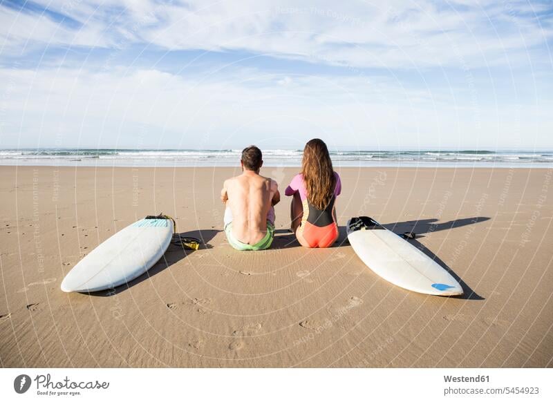 Paar mit Surfbrettern am Strand sitzend sitzt surfboard surfboards Beach Straende Strände Beaches Pärchen Paare Partnerschaft Surfer Wellenreiter Surfen Surfing