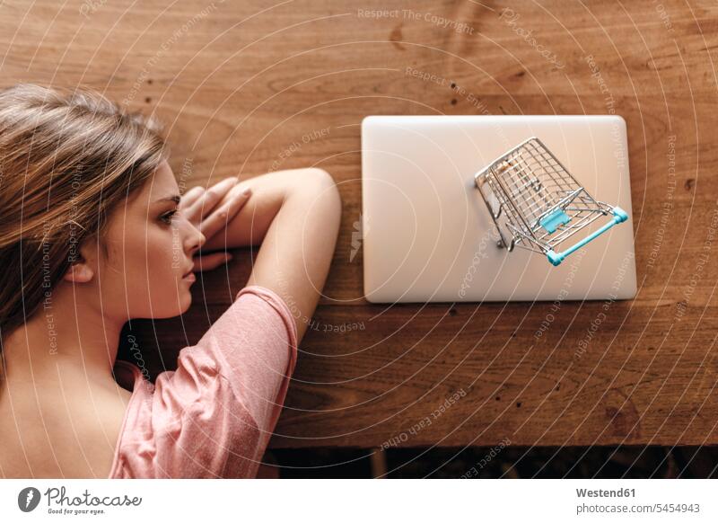 Junge Frau betrachtet Einkaufswagen am Laptop, online einkaufen Einkaufen shoppen shopping Online jung Warenkorb Notebook Laptops Notebooks weiblich Frauen Kauf