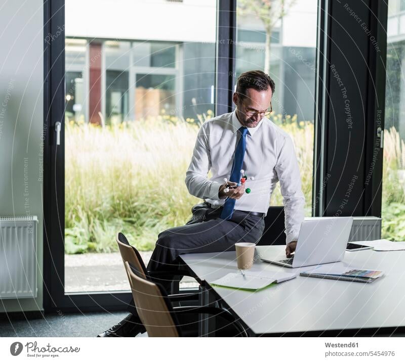 Geschäftsmann mit Atommodell mit Laptop in seinem Büro Businessmann Businessmänner Geschäftsmänner Office Büros Geschäftsleute Geschäftspersonen Geschäftsleben
