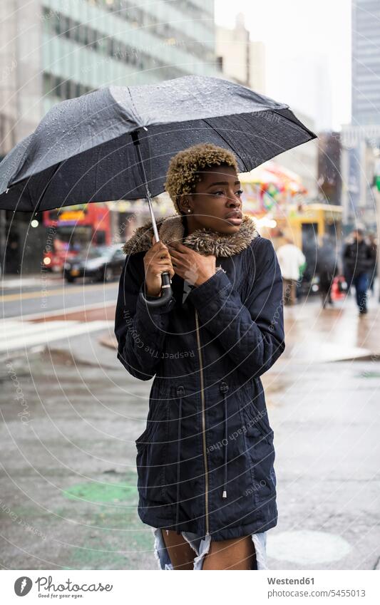 USA, New York City, Porträt einer jungen Frau mit Regenschirm an einem regnerischen Tag Regenschirme verregnet verregneter Portrait Porträts Portraits Schirm