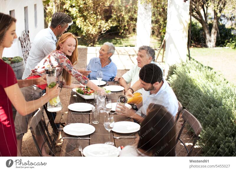 Glückliche Familie bereitet das Mittagessen auf dem Gartentisch vor Spaß Spass Späße spassig Spässe spaßig Familien feiern Gartenparty Gartenpartys Gartenfest