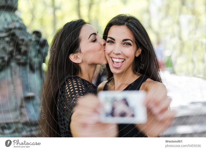 Zwei glückliche Zwillingsschwestern halten ein Sofortfoto in der Hand Freundinnen Foto Fotos Schwester Schwestern Freunde Freundschaft Kameradschaft Bild